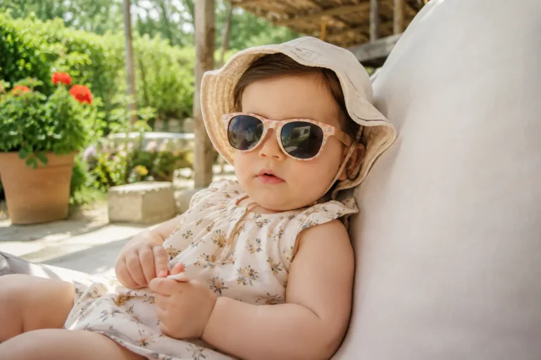 Bébé protégé de la chaleur en été avec chapeau, lunettes de soleil et tenue légère.